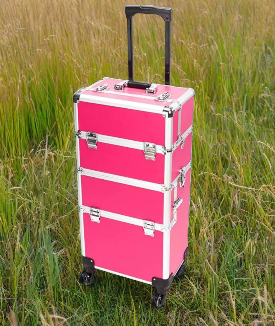 Pink rolling suitcase with black handle and wheels on a grassy background